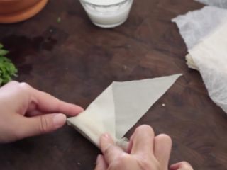 11、极简单做几个泰国爆竹虾,卷到大概三分之的位置，把三角形的顶端向右折，不能留下多余的空间，不然容易“露馅”