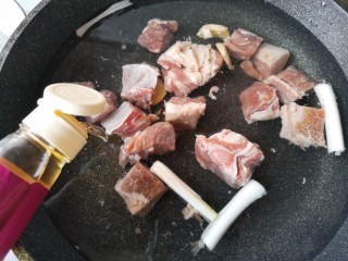 2、冬至美食 家常红烧牛肉,将洗净的牛腩凉水下锅，加入葱段，姜片和料酒。