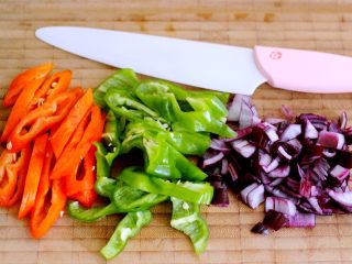 4、香爆咖喱花蛤,用刀把青椒、红椒切成丝、洋葱切丁