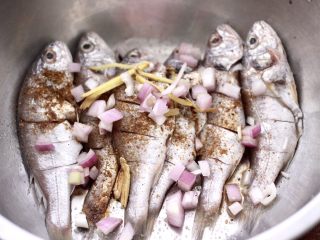 9、香辣孜然烤鱼,把切碎的洋葱和姜丝倒入盆里,用手抓匀后腌制30分钟。