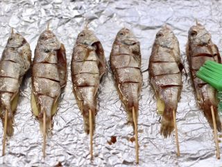 12、香辣孜然烤鱼,把串好的鱼,再刷上一层薄薄的黄油。