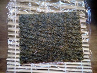 8、樱花寿司,翻转过来,让保鲜膜在下面,海苔在上面。