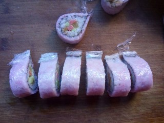 12、樱花寿司,切寿司的时候,保鲜膜不要揭下来,这样切的寿司整齐不容易散掉,要用比较锋利的刀切。