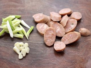 2、干煸烤肠茄条双椒,藤椒烤肠用刀切成薄片，大蒜去皮后切成片，葱切丝。