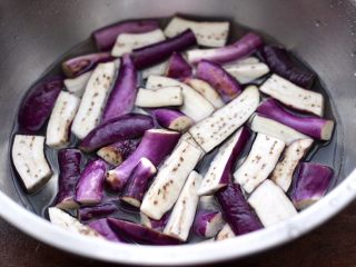 4、干煸烤肠茄条双椒,盆中加入适量的清水，倒入几滴柠檬汁，把切条的茄子放入，这样做的茄子不会氧化发黑呀。