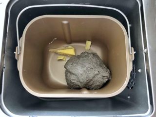 6、黑芝麻吐司(一次发酵),启动面包机的揉面程序,把干酵母揉进面团里即可停止揉面,接下来放入黄油。