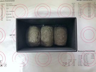 14、黑芝麻吐司(一次发酵),收口朝下码入吐司盒中,盖上保鲜膜室温下进行发酵。