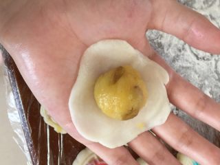 11、我叫可爱的葡萄干奶黄冰皮月饼,接下去我们就可以包啦 把奶黄馅搓搓圆 冰皮压压扁 馅放皮中间虎口收回来揉揉圆 再在根据你月饼模的图案放点刚揉好彩色的冰皮
