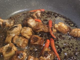 15、酸酸甜甜青椒排骨,冰糖融化后立刻倒入排骨。因为拍照，我倒入时间迟了点，已经有点变焦了。哈哈