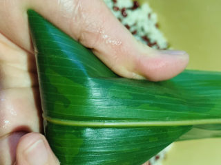 17、红豆粽子,上面的剩余粽叶往下压,并捏紧两边