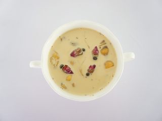 9、养颜鱼胶奶冻,把红枣去掉,加几粒玫瑰花装饰一下。盖上保鲜膜,放入冰箱冷藏4小时,直到完全凝固成果冻的状态。