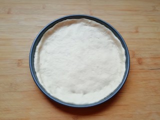 6、培根肉披萨,发酵好的面团揉光排气，擀成一张比模具大一些的面饼，放进披萨盘里，用手把大出来的部分压实，使其贴在披萨盘的边上。