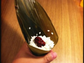 5、端午节 枣粽,手握住粽叶,先加入少许糯米垫底,加入大枣,再填满糯米