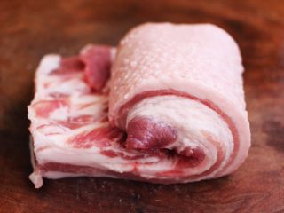 1、香卤五花肉,五花肉洗净后，用厨房用纸吸干水分，开始从一边卷起。