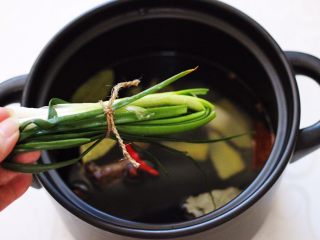 7、香卤五花肉,这个时候把葱打结放入砂锅里。