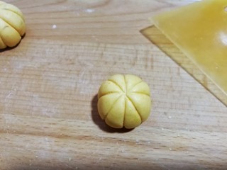 11、南瓜豆沙小汤圆,然后用刮板呈“米”字形，在糯米团上压出南瓜形花纹（操作时左手拿糯米团，右手拿刮板从上往下轻轻推挤着压出花纹，一个人拍照不好拍出此步骤细节）