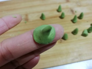 16、南瓜豆沙小汤圆,再把底部捏薄，凹成一个图钉形状，抹点水沾在南瓜汤圆团上