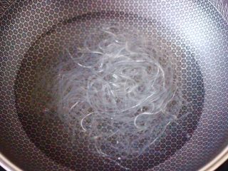 3、韭菜粉条发面包,锅中倒入适量清水，把粉条放入锅中煮一下，看见粉条变得透明关火，盛出沥干水分，用刀切碎备用。