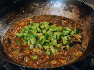 8、肉末茄子,加入1汤匙生抽,1茶匙黑酱油,2汤匙蚝油,2杯水 。加入青椒。把所有的东西混合好,盖上盖子,用中火炖15分钟, 直到茄子变软。 锅里要保证足够的酱汁。