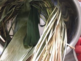 2、肉粽子,粽子叶（包粽子的叶子）和棕叶（图中长条的，捆粽子用的）用水泡，待变软后洗净备用