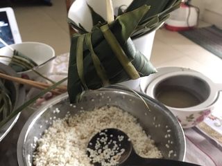 10、肉粽子,绕完三圈棕叶可能还剩一截，直接拉棕叶的根部那，拉紧就行，后续粽子就通过这个棕叶根部与别的粽子绑到一起