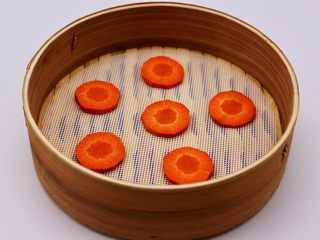 10、清新碧绿的青叶汁黑芝麻豆沙青团,胡萝卜提前用刀切成6片铺在蒸笼上面