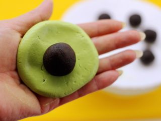 12、清新碧绿的青叶汁黑芝麻豆沙青团,把面团用手摁扁放入豆沙黑芝麻馅料