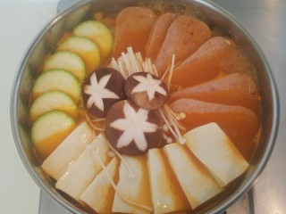 11、泡菜锅,再把午餐肉，豆腐，西葫芦，香菇和金针菇码好，盖上锅盖改成中火咕嘟几分钟。