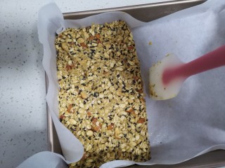 10、燕麦棒,倒入铺好油纸的烤盘里，整理成长方形