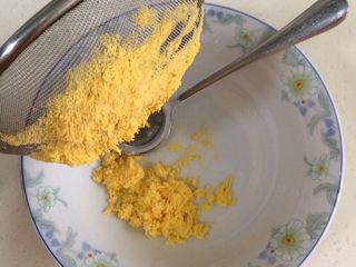4、蔓越莓玛格丽特,把鸡蛋黄放入面粉筛,用勺压成粉状。