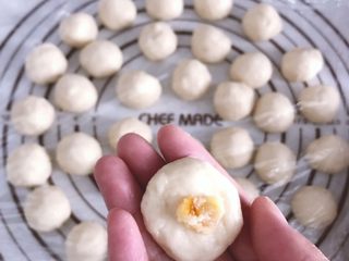 11、乳酪橙皮金钱小面包,取一个小面团，轻轻拍扁，放入奶酪橙皮馅后捏紧收口，滚圆。