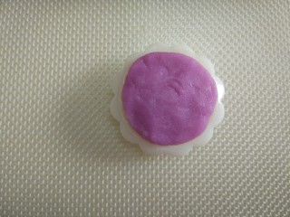 8、五彩冰皮月饼,取一个彩色面团，分割成两份，每个5克，揉成圆形，轻轻的按压在月饼模具的花片上，力度要均匀分布。（每种彩色面团是10克，每种颜色可以印出两个月饼）