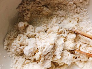 3、芝士培根披萨,多次少量加温水,用筷子搅拌成如图所示面块,底部还有少许面粉状态。(用温水揉面更易发酵)