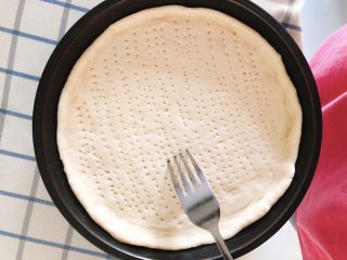 9、芝士培根披萨,将面饼装入烤盘,面饼四周略高于底部翘起,用叉子在面饼底部戳一些小点,以防烤制时底部膨起。