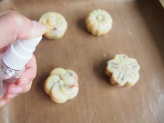 12、蛋黄豆沙月饼,将压好的月饼放在烤盘上,烤箱预热到160度,喷上一层清水,烘烤5分钟定型