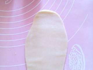 5、苏式鲜肉月饼,把卷好的面团，用擀面杖擀成长椭圆形面片。再次把面片卷起来。盖保鲜膜静止一会。