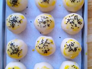 9、苏式鲜肉月饼,将包好的面团收口朝下放在烤盘上，在面团表面刷一层蛋黄液，再撒上一些者黑芝麻。