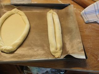 8、土耳其披萨,放在烤盘上,将卷好的两条圆卷往外摊开,变成一个中间平坦周围有垣的椭圆面皮。