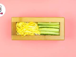 3、懒人免卷箱寿司,模具中铺一层寿司饭，放上海苔1片，再铺一层寿司饭，然后一半铺黄瓜片，一半铺蛋皮，压实取出备用