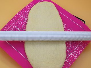 4、日式炼乳吐司,发好后的面团取出排气，尽可能擀成长方形（取出的动作不是用手直接去把面团扯出来而是用软刮板或者手指从面团的底部往上捞出来）。
