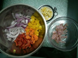 4、咖喱披萨,面团发酵时间准备披萨馅料。玉米粒洗干净,培根切成小块,红黄椒切小块,洋葱留一些切成长条状,其余的切成小块状。