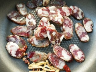 6、豉香腊肠炒蒜苗,放腊肠下锅，继续小火煸炒。
