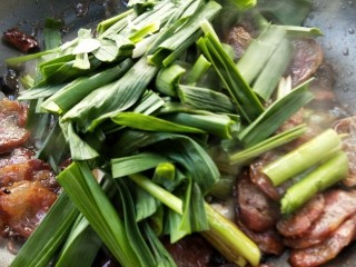 12、豉香腊肠炒蒜苗,接着放蒜苗绿叶部分。