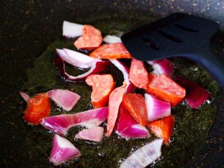 4、时蔬罗勒炒意面,锅中倒入橄榄油油烧至六成热时，先倒入洋葱翻炒出香味，加入肉肠继续翻炒片刻。