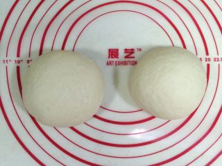 4、培根口蘑田园披萨,取出面团进行排气，把面团平均分成2份。