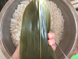 15、肉粽子,重点来了，把后面的叶子盖过来顺势用手压住右边的叶子