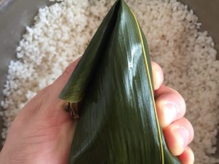 17、肉粽子,把前面多余的长出来的叶柄折过来，这样一个粽子就包好了，拿过来事先准备好的棉线