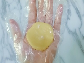 13、豆沙蛋黄月饼,取一块皮放在手心按扁，（我带的一次性手套嫌带手套不好操作的在手上拍点熟面粉防粘）