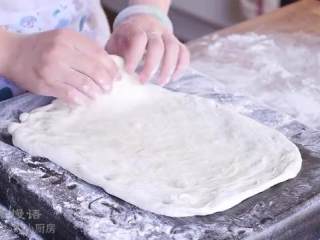 9、春日田园披萨,把面饼拿起来捏着边转动，让它延展开来，平摊在烤盘底上，整形成长方形