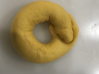 12、南瓜圈圈面包,卷起来，另一头放在压扁的面团上，用压扁的面团包好并收口。